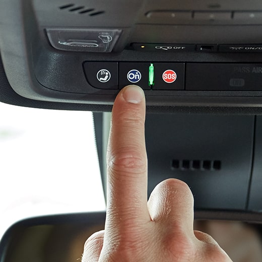 Driver Pressing OnStar Services Button in GMC Vehicle 