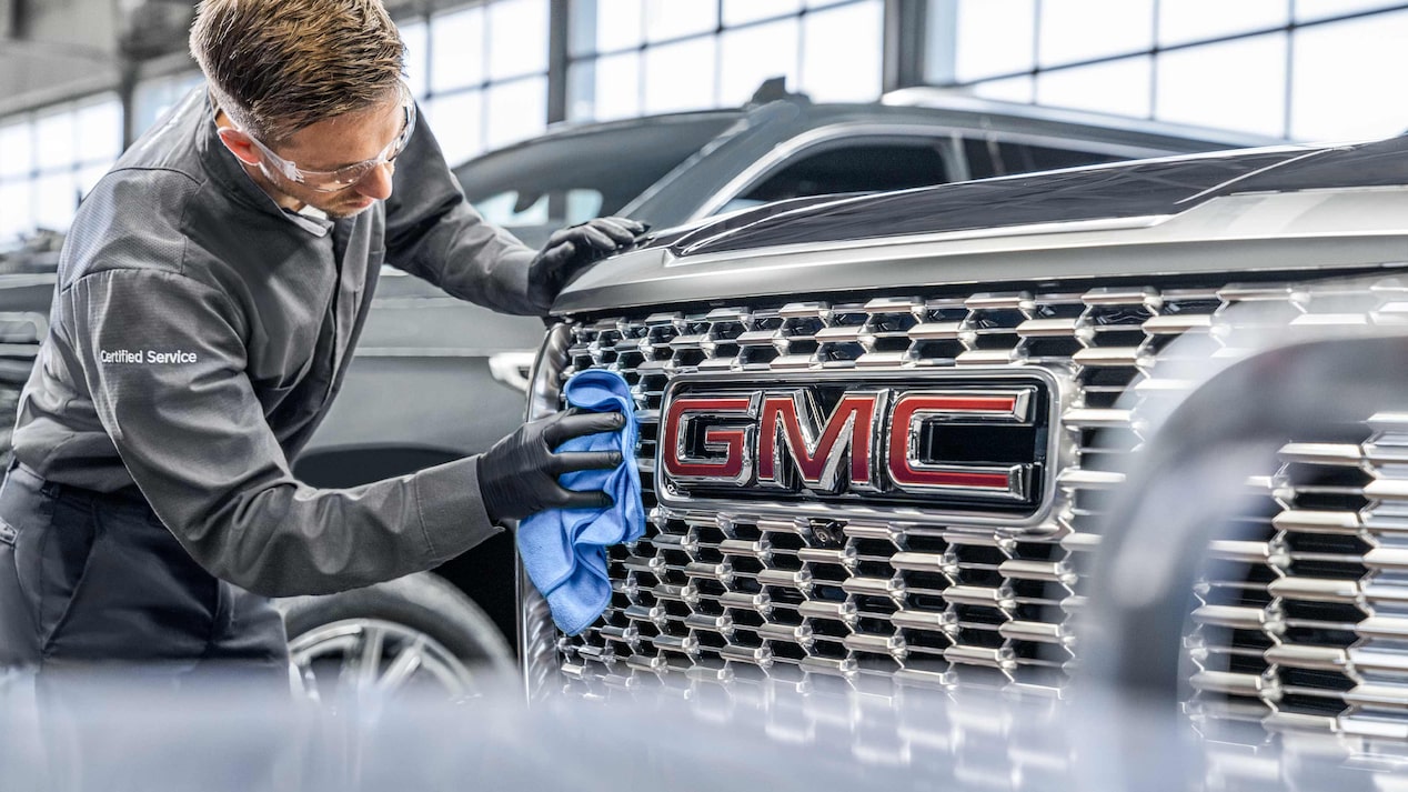 A GMC Certified Service Technician Wiping the Grille of a Vehicle with a Cloth