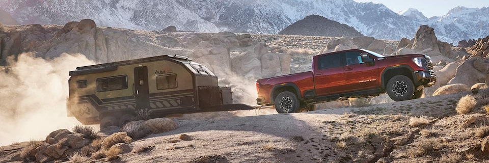 Profile View of the GMC Sierra HD AT4X AEV Towing a Trailer Through the Mountains