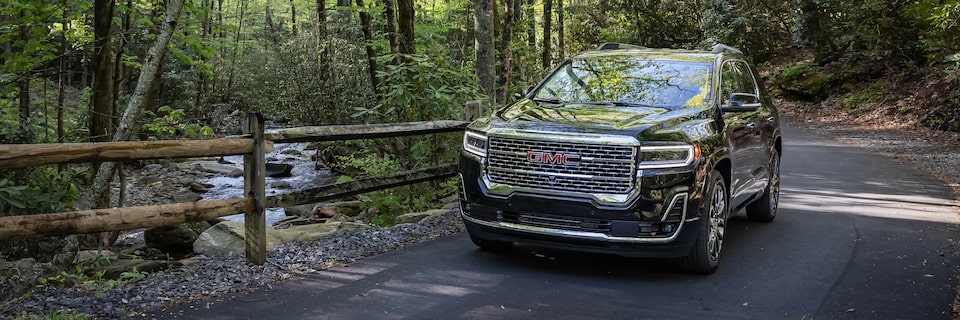 A GMC Acadia Denali SUV Driving on a Path Surrounded by Trees