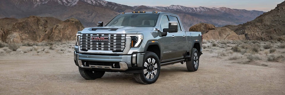 Front Three-Quarters View of a GMC Denali Truck Parked on Dirt With Mountains in the Background