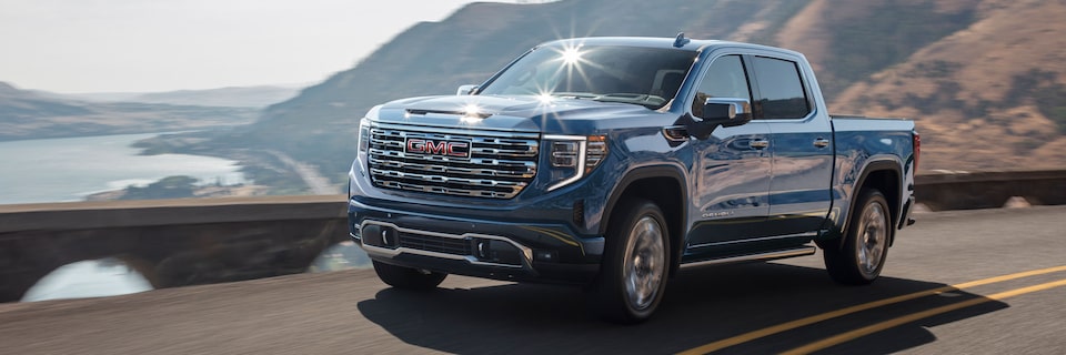 Front View of a GMC Denali Truck Driving on a Road Next to a Cliff