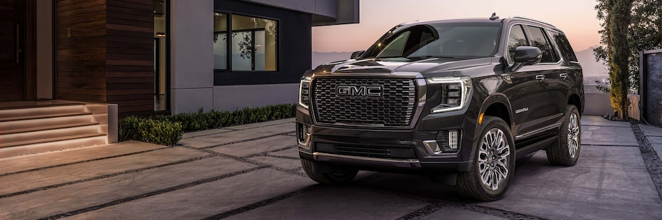 A GMC Denali SUV Parked In Front of a Luxury Home at Sunset