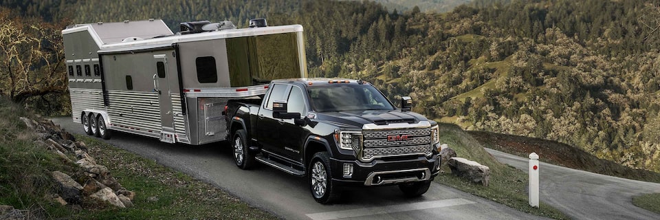 GMC Sierra HD Truck Towing Trailer along mountain road