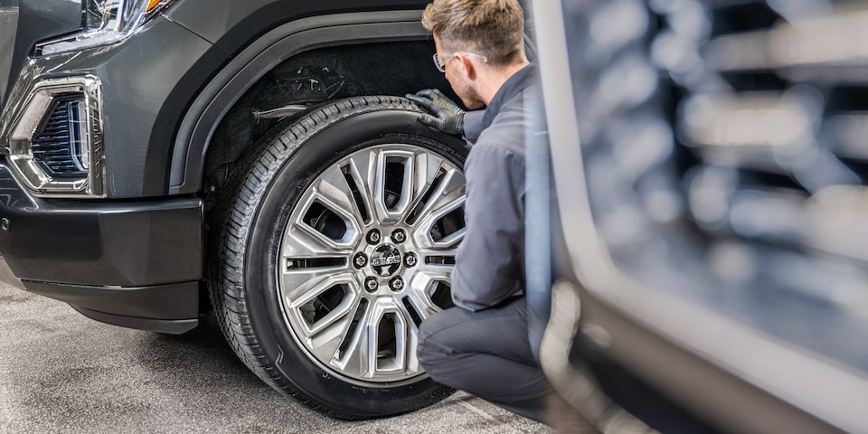 GMC Certified Service Technician Inspecting a Wheel on a Vehicle