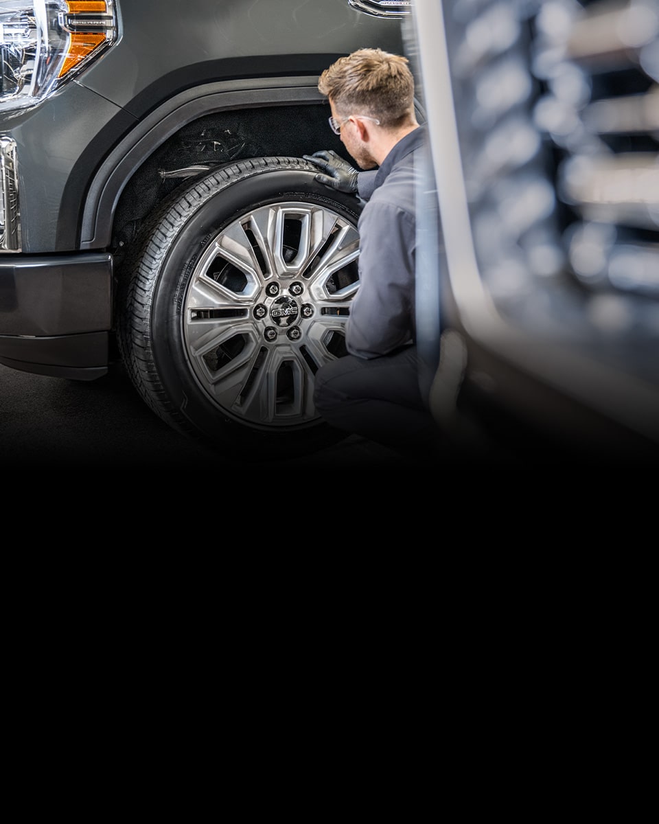 GMC Certified Service Technician Inspecting a Wheel on a Vehicle