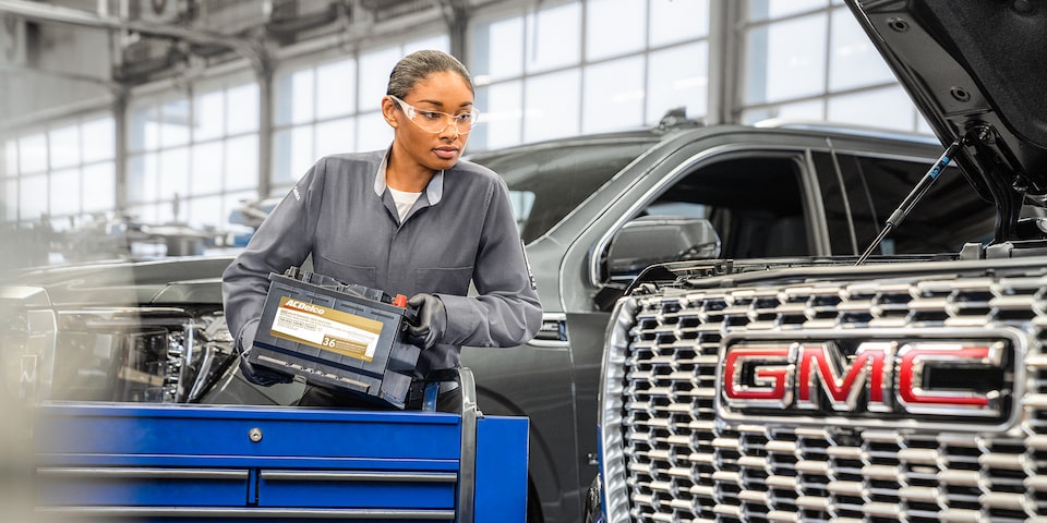 GMC Certified Service Carrying an ACDelco Gold Battery to Install in a Vehicle