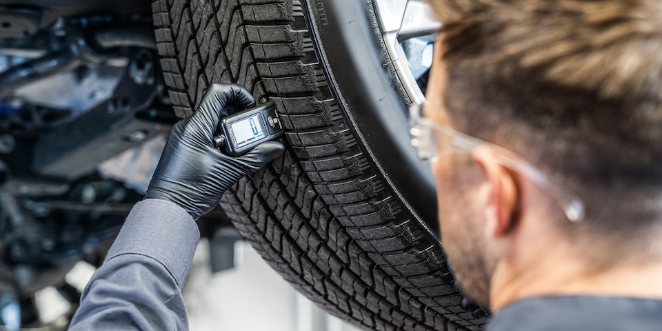 GMC Certified Service Technician Checking the Tread Level on a Tire