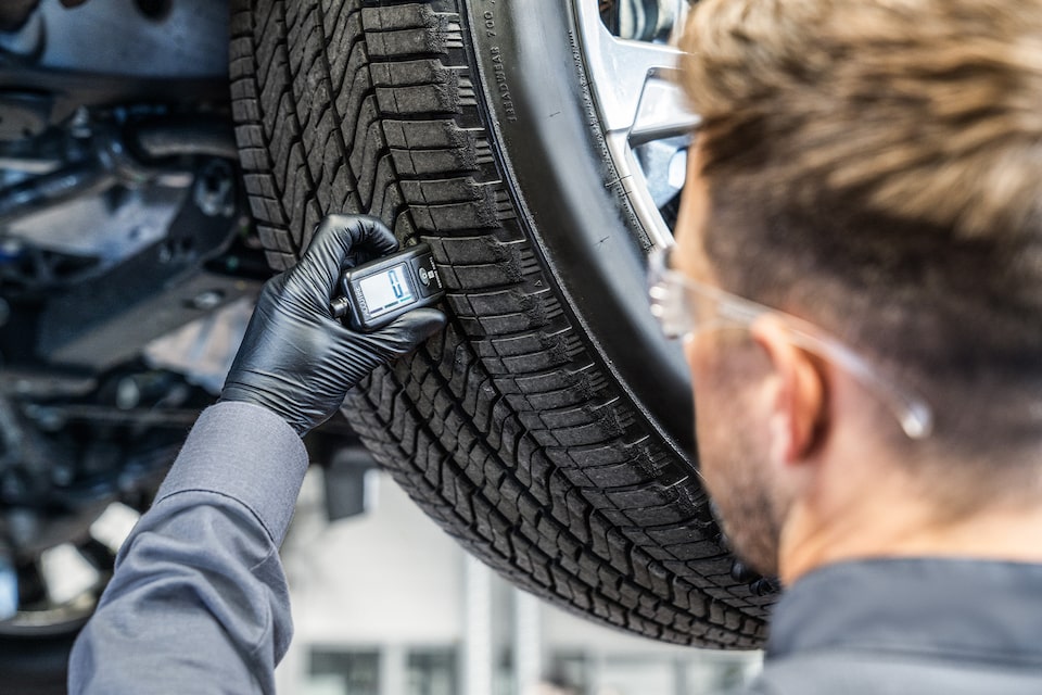 GMC Certified Service Technician Checking the Tread Level on a Tire