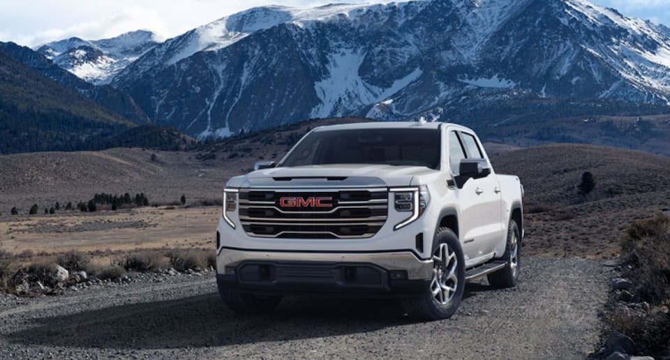 GMC Truck Driving on a Gravel Road with Snow Covered Mountains in Background