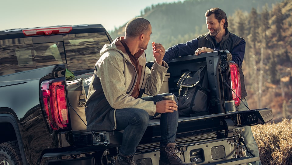 Men Sitting in Bed of GMC Sierra Truck with Hiking Gear