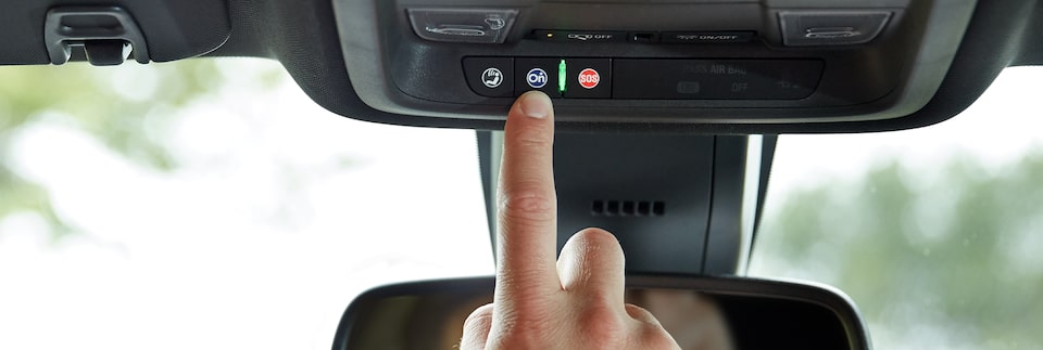 Driver Pressing OnStar Services Button in GMC Vehicle 