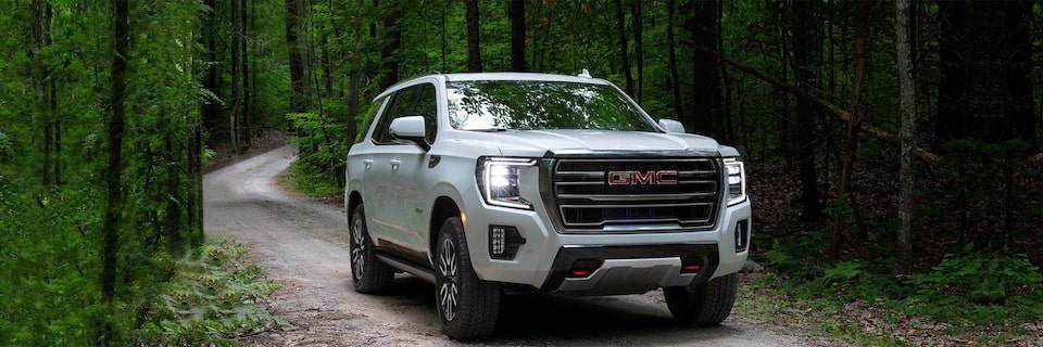 A GMC Yukon AT4 SUV  Driving on a Tree-Lined Path