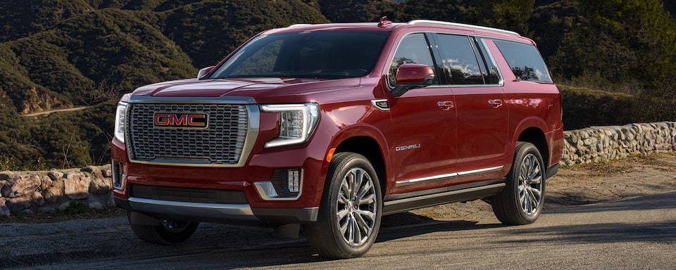 Close-up of a GMC Yukon SUV Parked on a Gravel Path with Mountains in the Background