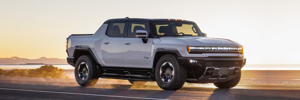 A Hummer EV Pickup Truck Driving on an Open Road During Sunset