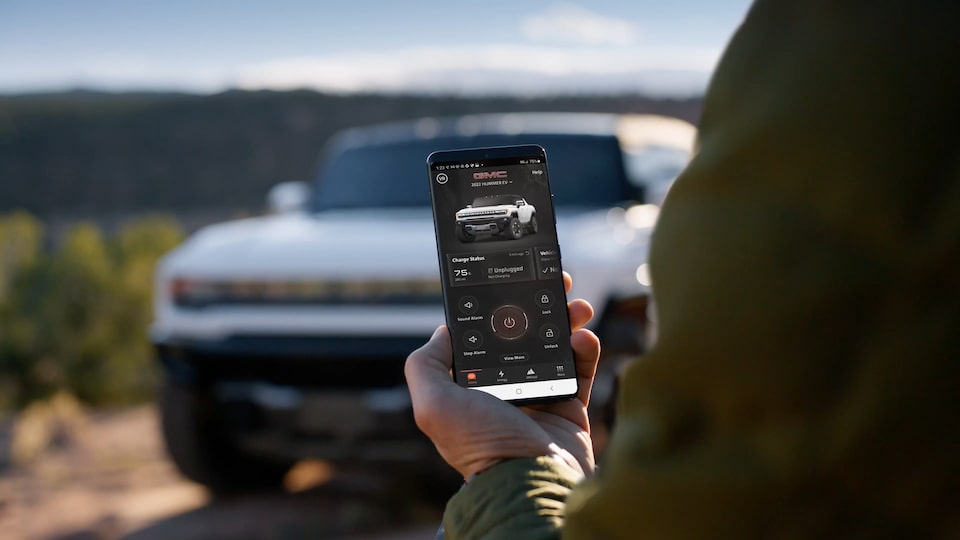 A Person Holding a Phone Using the Mobile App for the GMC Hummer SUV with the Vehicle Visible in Front