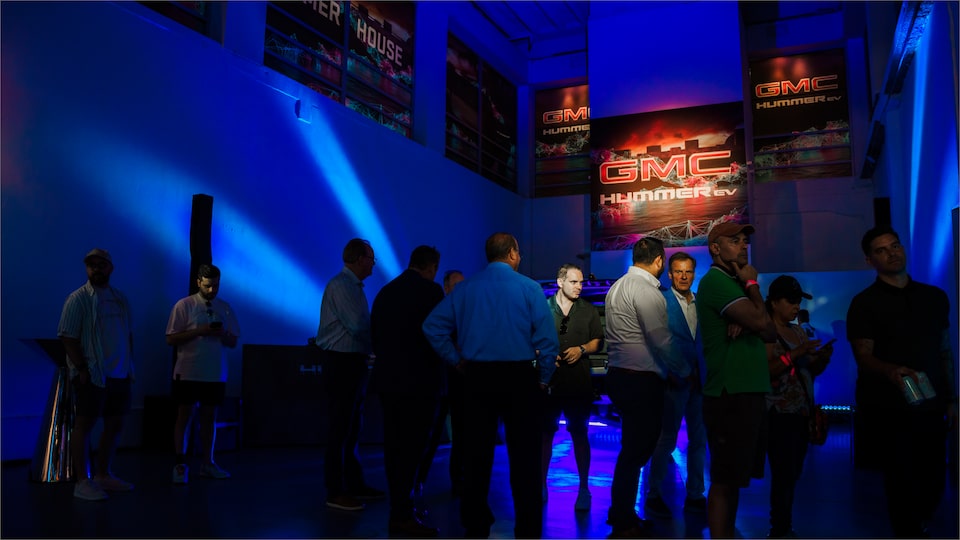 A Group of People in a Packed Lit Up GMC Showroom