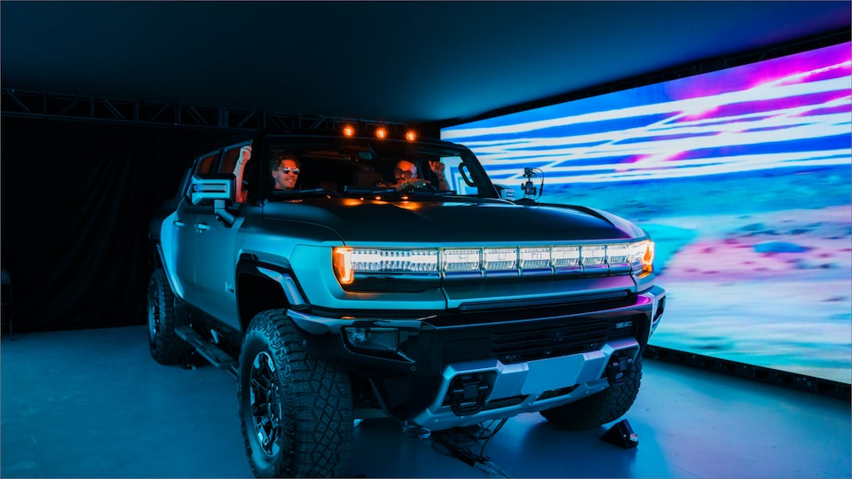 Two People Sitting in a GMC HUMMER EV inside a Showroom