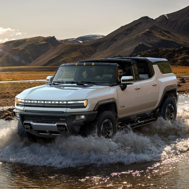 The GMC HUMMER EV SUV Driving Off-Road through Mud and Water