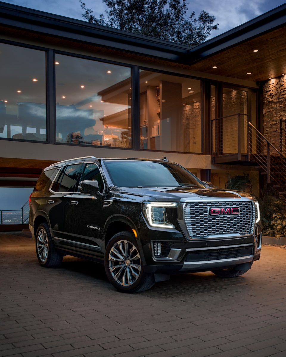 A GMC Yukon SUV Parked in Front of a Modern Home at Sunset