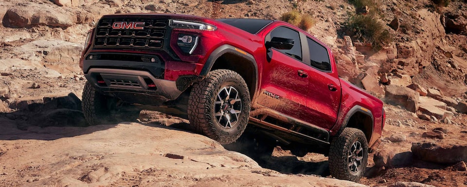 A Red GMC Canyon AT4 Driving Uphill Off-Road on Rocks