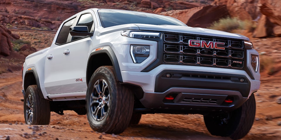 A White GMC Canyon AT4 Driving Off-Road on Rocks