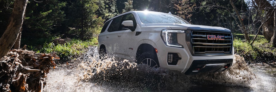 GMC Yukon AT4 Driving on a Muddy Trail Through the Woods