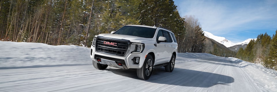 The White GMC Yukon Denali Driving On Snow