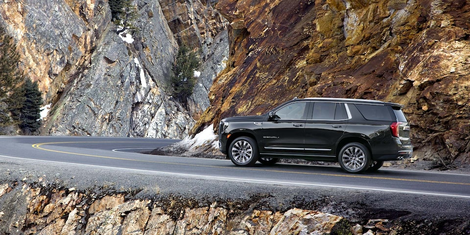 A Side View of the Black GMC Yukon Denali Driving On-Road