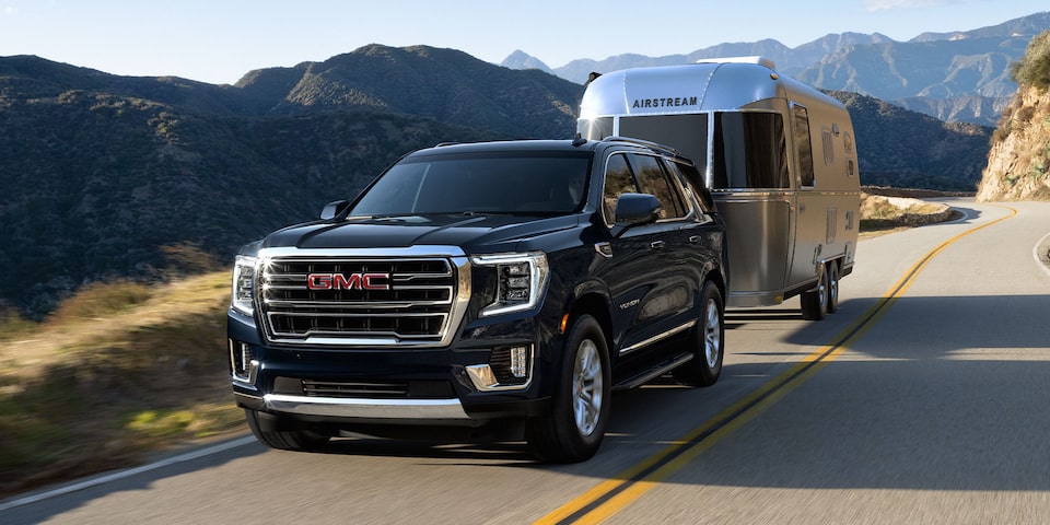 A GMC Yukon Denali Driving On-Road Towing a Trailer