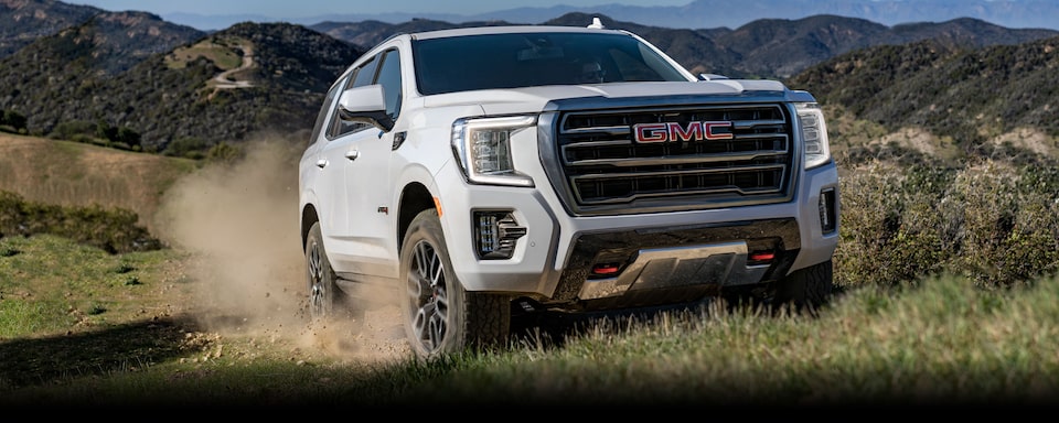 The White 2024 GMC Yukon Driving Off-Road on Grass