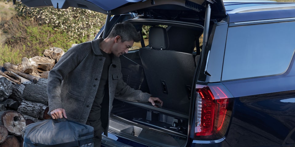 A Man Unloading a 2024 GMC Yukon Trunk During the Day