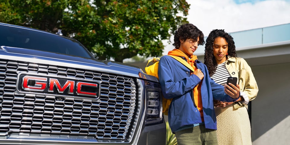 Two People Standing Next to the Front of a GMC Vehicle