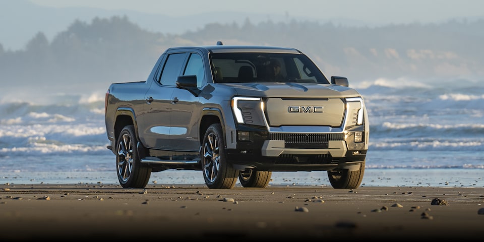 Wide Front Three-Quarters View of the GMC Sierra EV Truck Driving on a Beautiful Beach