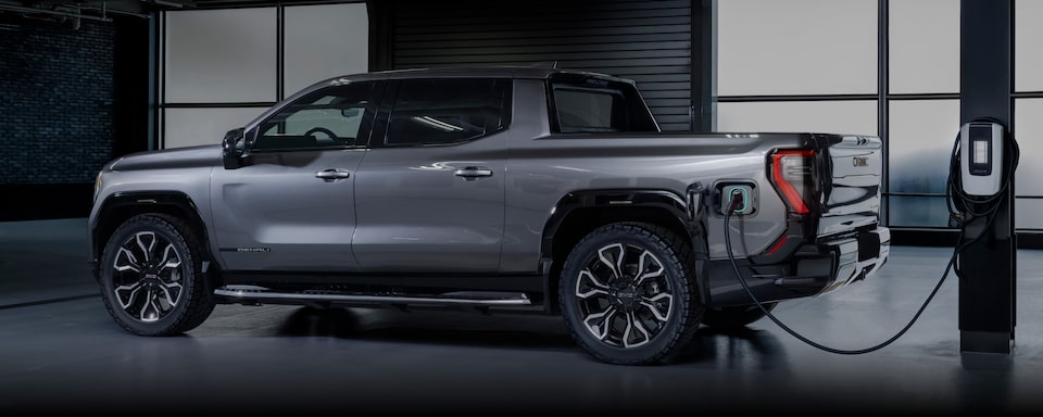 A GMC Sierra EV Parked Inside a Garage Plugged Into a Charging Unit