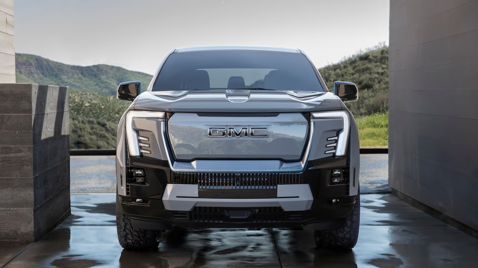 Front View of the GMC Sierra EV Truck Pulling Up to a Building