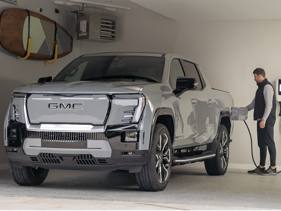 A Person in Their Garage Connecting the Charger to Their GMC Sierra EV Truck