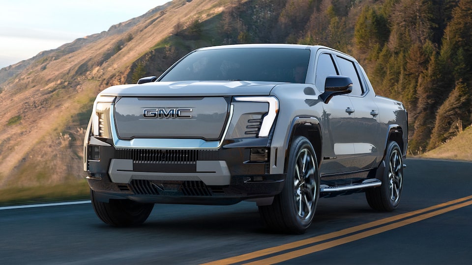 Front Three-Quarter View of the GMC Sierra EV Pickup Truck Driving up a Winding Mountain Road